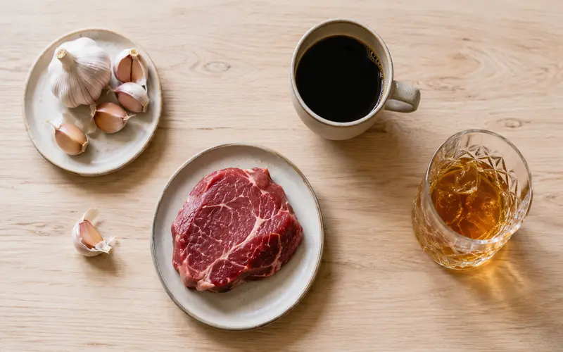Flat lay com alho, carne vermelha, café e álcool representando alimentos que causam suor com cheiro forte